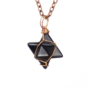 Macro detail of hand-wrapped copper wire on a black hexagonal star stone pendant