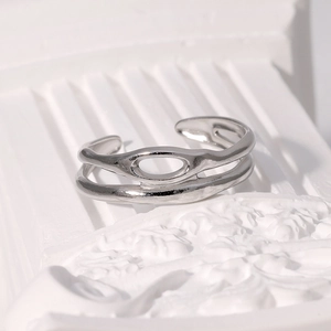 Détail d'une bague double couche en acier argenté ajouré sur un support en marbre