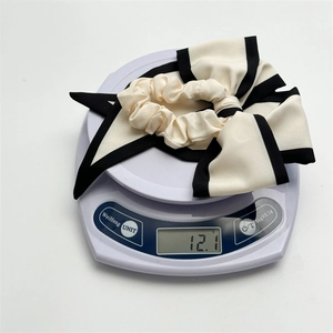 Off-white oversized bow scrunchie with black trim on a digital scale weighing 12.1g