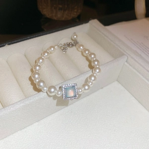 Detail of a pearl necklace with a light blue square gemstone pendant and silver extension