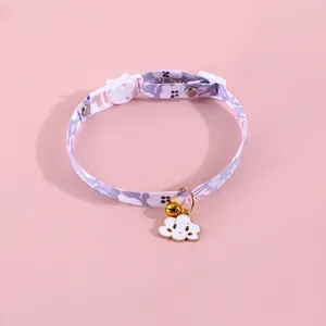 Close-up of lavender floral pet collar with white cloud pendant and golden bell detail