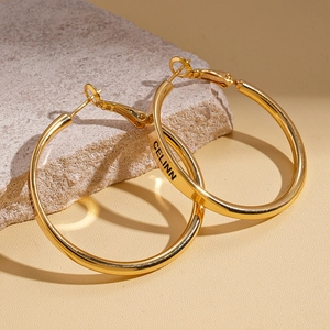 Macro shot of CELINN logo engraved on polished gold circular hoop earring surface