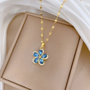Macro detail of gold necklace with a blue stone rotating flower pendant and crystal inlay