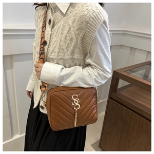 Close-up of brown V-quilted crossbody bag with gold SSS logo and stylish tassel detail