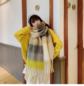 Detail of colorful plaid scarf featuring thick tassels and warm knit texture