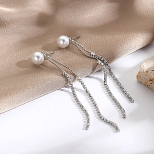 Detailed shot of pearl and rhinestone tassel earrings on elegant silk background
