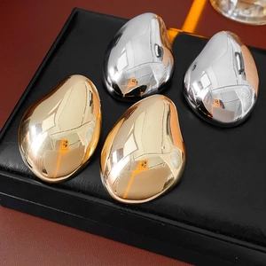 Macro detail of metallic teardrop earrings in gold and silver finish on display