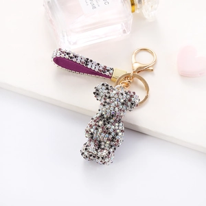 Close-up of sparkling rhinestone bear keychain with purple plaid strap and gold metal hardware