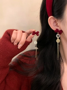 Close-up of festive red velvet bow earrings with Xi character and long gold tassels