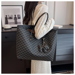 Detail of grey monogram tote bag featuring M-pattern and cute elephant charm accessory