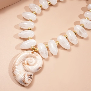 Macro view of white teardrop acrylic beads and large conch pendant necklace