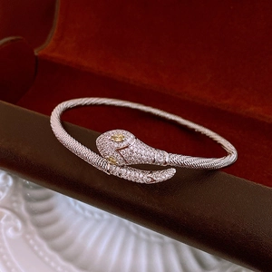 Macro shot of silver snake bracelet with white zircons and yellow gemstone eyes