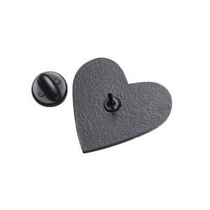 Detail of heart-shaped metal pin back with black rubber clutch on white background