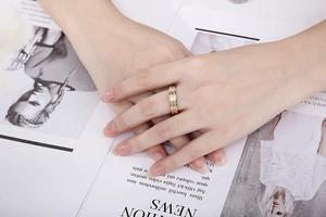Detail of a two-tone stainless steel ring with frosted texture on a model hand