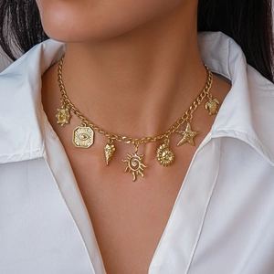 Detail of golden necklace featuring starfish, sea shell, and turtle charms on a white shirt