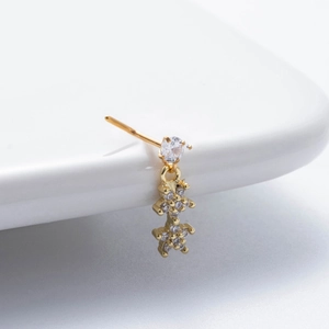 Détail macro du piercing de nez en L doré avec pendentif fleur en zircon sur céramique