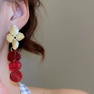 Close-up of vintage flower earrings with dark red beads on a model's ear