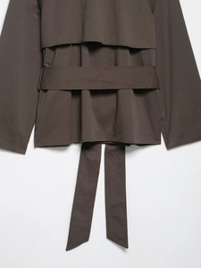 Detail eines dunkelbraunen kurzen Trenchcoats mit Webstoff und passendem breitem Taillengürtel
