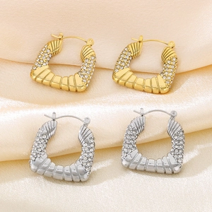 Detail showing gold and silver C-shaped diamond earrings with textured horizontal patterns