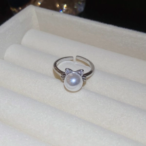 Macro detail of silver adjustable cat-ear ring with a white pearl in a jewelry box