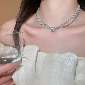 Close-up of elegant double-layer pearl necklace with a sparkling diamond heart pendant