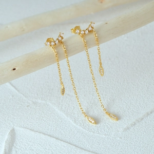 Detailed view of gold-plated silver tassel earrings with crystal crescents and leaves