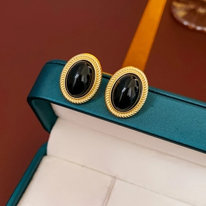 Macro view of vintage oval black stone earrings with gold twisted metal edges