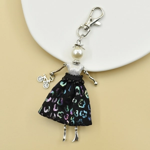 Detail of handmade doll keychain with leopard sequins and miniature bicycle charm