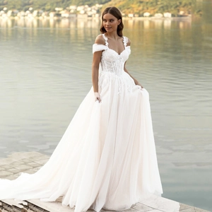 Detail of off-the-shoulder lace bodice and layered tulle skirt on a white bridal gown