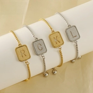 Detail of adjustable 18K gold plated stainless steel box chain bracelets with letter charms