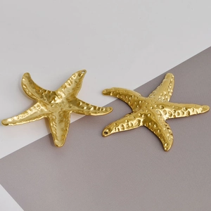 Detailed macro of golden starfish pendants with hammered metal texture for DIY jewelry