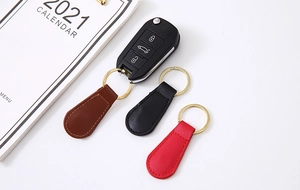 Tear-drop leather magnetic keychain in brown, black, and red with gold ring on a car key