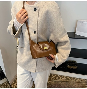 Detail of brown patent leather crescent bag with golden clasp and adjustable shoulder strap