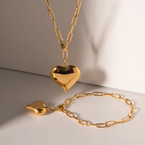 Golden paperclip chain jewelry set featuring polished hollow heart pendants on necklace and bracelet