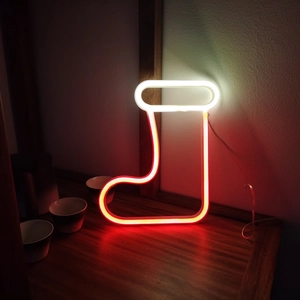 Neon Christmas stocking light with red and white LED glow on a wooden table setup