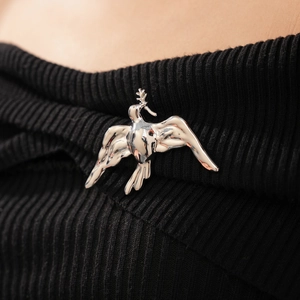 Close-up of a silver polished bird brooch with branch on black knitwear garment