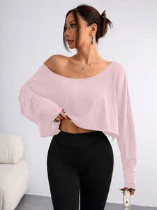 Detail of pink long-sleeved off-shoulder crop top paired with black high-waisted yoga pants