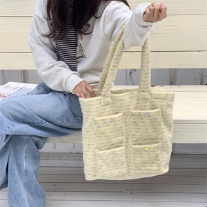Detail of plush beige tote bag with colorful polka dots and four functional front pockets