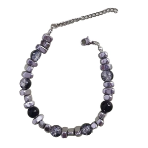 Beaded bracelet with silver metallic cylinders and black cracked beads on white background