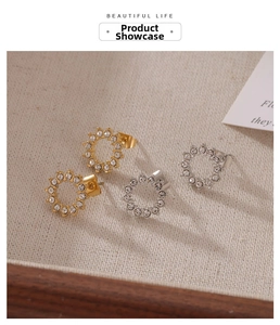 Détail des boucles d'oreilles créoles strass or et argent sur tissu en lin texturé