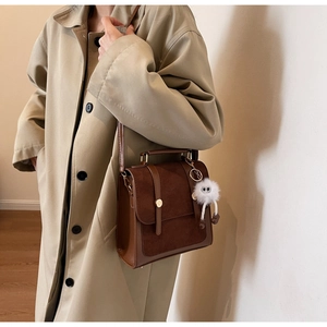 Detail of vintage brown suede backpack featuring gold hardware and a plush monster charm