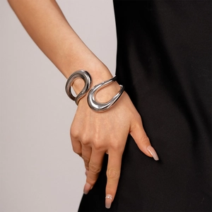 Close-up of a silver irregular geometric crossover bangle with polished metallic finish