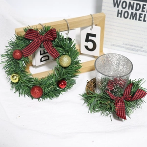 Detail of mini Christmas wreath with red plaid bow, gold baubles, and glass candle holder