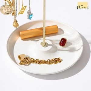 Detail of elegant gold double-row T-bar necklace holder on white ceramic tray