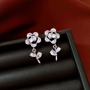 Close-up of zircon flower drop earrings on a black leather jewelry display box