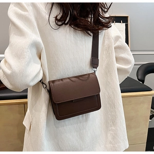 Brown PU leather crossbody bag with wide shoulder strap shown on a female model
