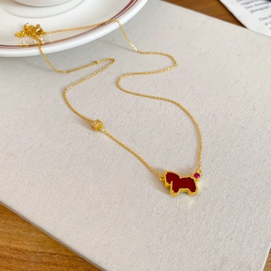Detailed macro view of the gold necklace with red horse pendant and ruby accents