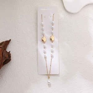 Detailed shot of 14K gold-plated long necklace with white pearls and geometric charms