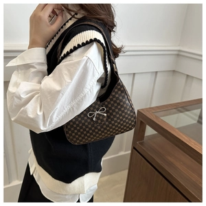 Detail of a brown patterned crescent shoulder bag with a silver metallic bow clasp
