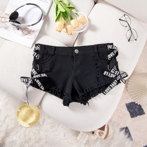 Dettaglio di pantaloncini di denim nero con lacci laterali e orlo a frange su una base